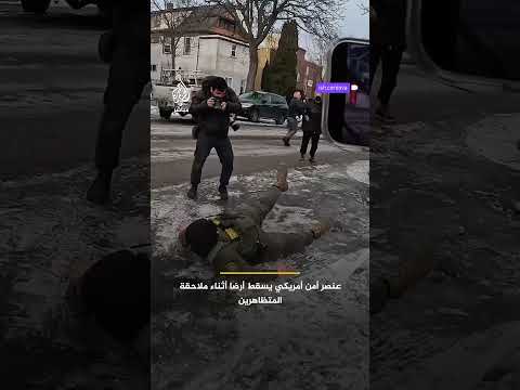 أحد عناصر وكالة الهجرة والجمارك الأمريكية يسقط أرضا بعد أن فقد توازنه خلال محاولة إمساك متظاهر